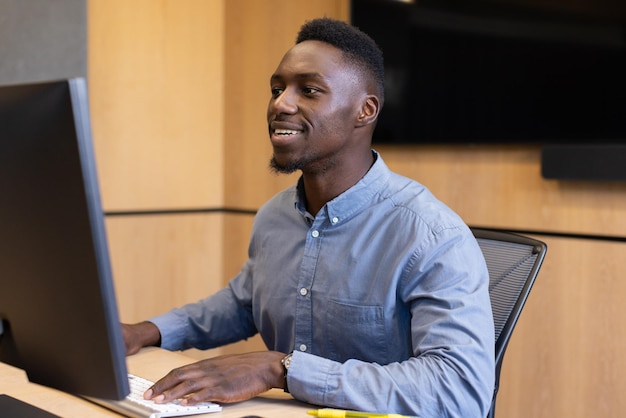 Working on computer african american man smiling and typing at office desk