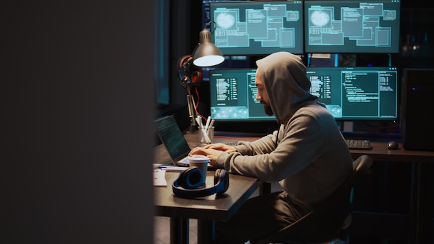 Young adult hacking password to break server interface, using virus to infect computer and steal big data. Dangerous mysterious hacker doing cyber attack on system security, IT fraud. Handheld shot.