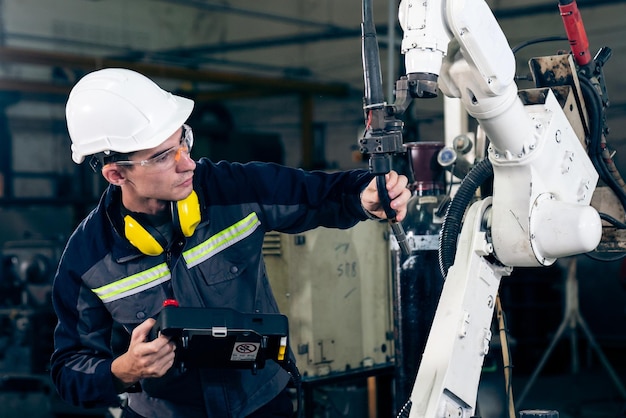 Young factory worker working with adept robotic arm