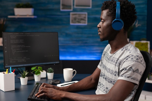 Young it hacker programming software for website security typing html code developing application. Businessman wearing headphones working at infographics javascript. Remote work from home