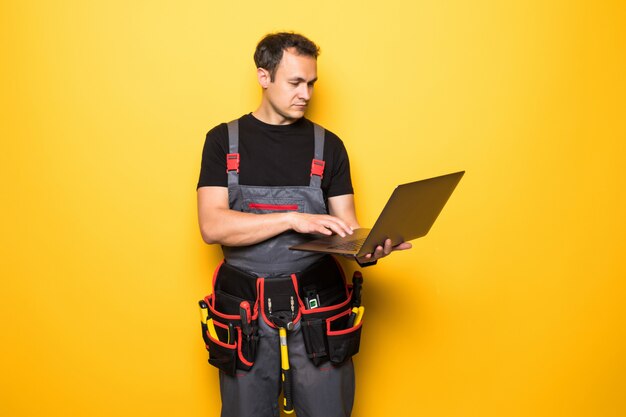 Young man worker with tools belt with laptop