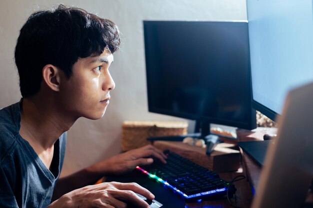 Young man working on computer in dimly lit room