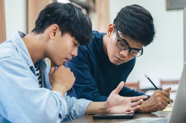 Young men discussing over mobile phone while sitting on table