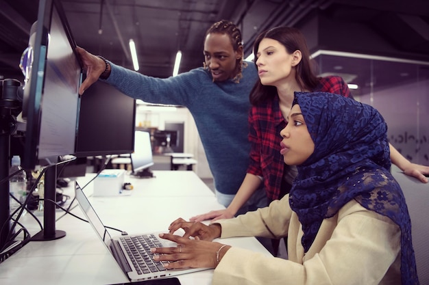 young multiethnics business team of software developers working together using laptop computer while writing programming code at modern startup office
