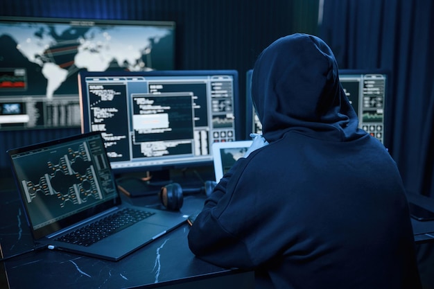 Young professional female hacker is indoors by computer with lot of information on displays