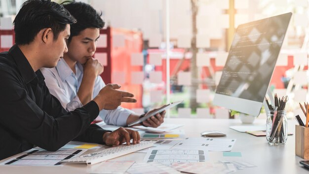 Young startup ux ui front end designers developing programming and coding responsive web content or mobile app from prototype and wireframe layout
