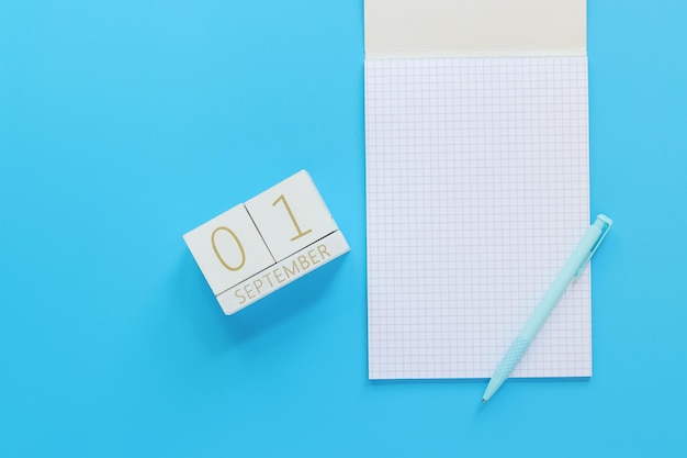 01 September Wooden calendar on a blue background with an open notepad top view