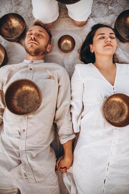 01062019 Vinnitsa Ukraine group therapy with Tibetan singing bowls for a girl and a boy lying on the ground in the middle of the desert surrounded by copper bowls meditation and relaxation