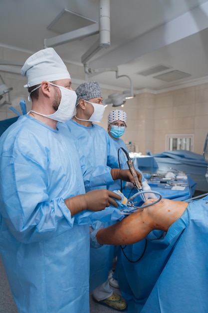 Photo 02012024 vinnytsia ukraine four surgeons work on surgical intervention in the knee injury of a male patient