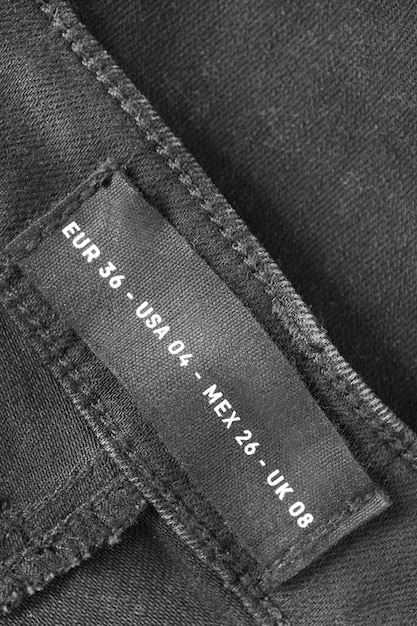 Фото Этикетка одежды размера 04 на черном джинсе на фоне крупного снимка