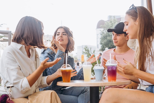 07082019 Vinnitsa Ukraine company of best friends pretty girls and guy gathered on the summer cafe terrace drinking refreshing summer drinks chatting joking having fun smiling