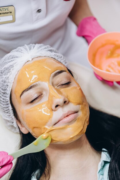 Photo 07102020 bar ukraine the process of applying a cosmetic mask on the face of a young girl who came to a beauty salon portrait of a happy satisfied customer