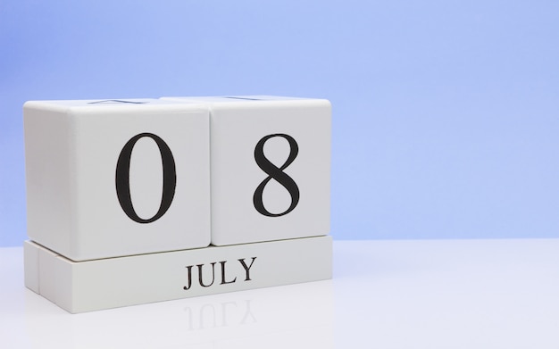 08 juli. Dag 8 van de maand, dagelijkse kalender op witte tafel met reflectie, met lichtblauwe achtergrond. Zomertijd, lege ruimte voor tekst