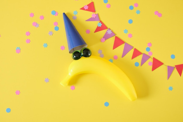 1 april date April Fools Day creative minimal concept creative postcard with a plastic banana in a cap with eyes on a yellow background