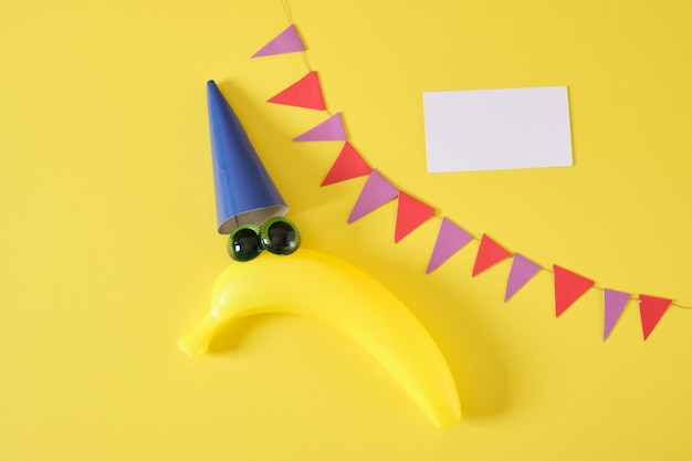 1 april datum April Fools Day creatief minimaal concept creatieve ansichtkaart met een plastic banaan in een dop met ogen op een gele achtergrond