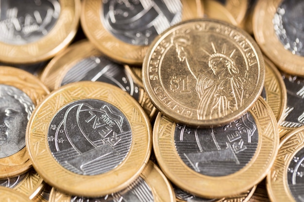 1 dollar coins in the middle of several 1 real coins on a wooden table