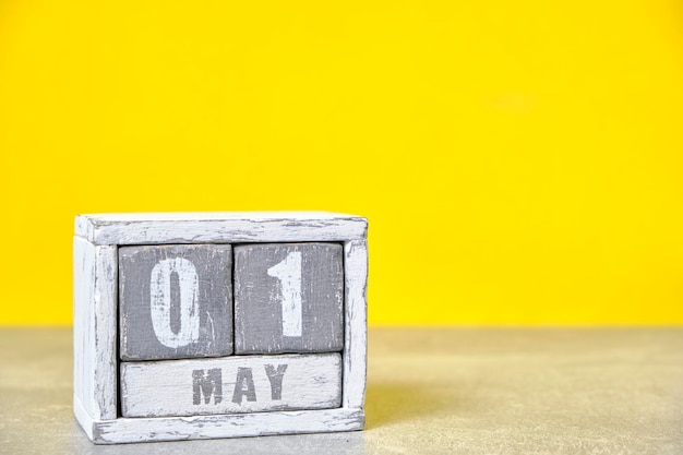 1 mei Houten bureaubladkalender gele achtergrondLentemaand afgebeeld op kubussenPlaats voor uw ideeënDag van de Arbeid