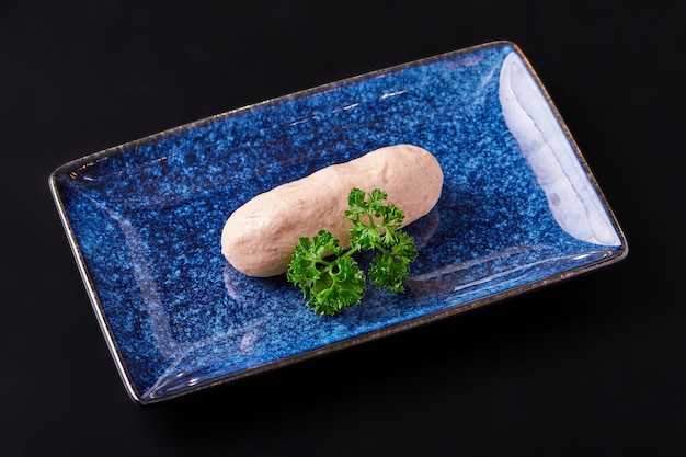 1本のワギュ牛肉ソーセージとローズマリーの葉を黒い背景に隔離したプレートに ソーセージは塩とスパイスと混ぜた小さい豚肉から作られ  ⁇ め物に ⁇ め込まれてバーに形成されます