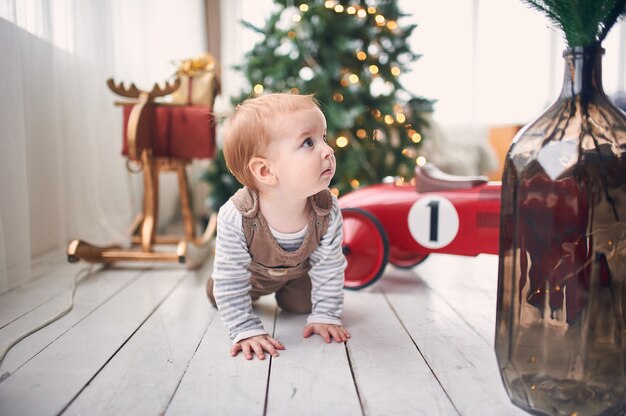 1歳の男の子が家の床の上でクロールします。