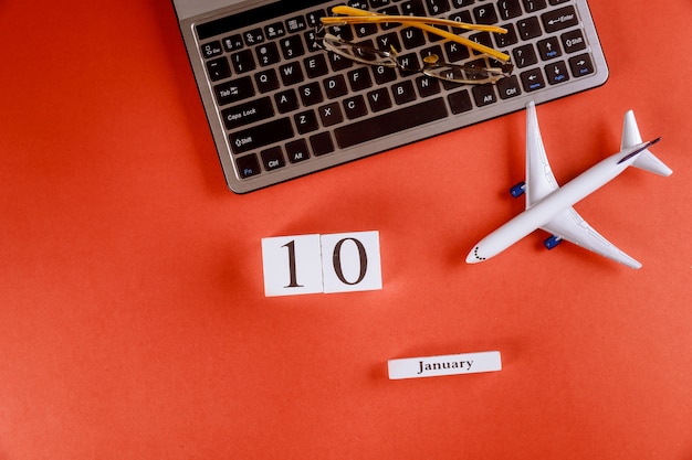 コンピューターのキーボード、飛行機、メガネ赤背景にビジネスワークスペースオフィスデスク上のアクセサリーと1月10日カレンダー