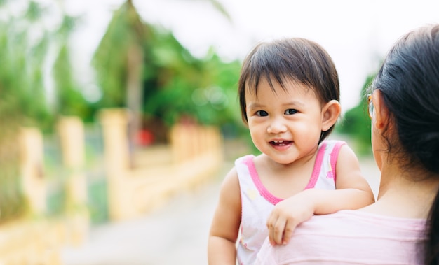 かわいい赤ちゃんが庭で彼女の母親と幸せと笑顔を感じる10ヶ月。