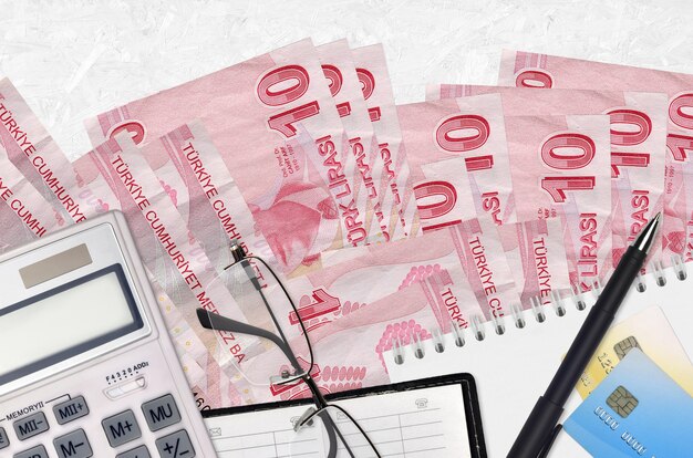 10 Turkish liras bills and calculator with glasses and pen. Tax payment season concept or investment solutions.