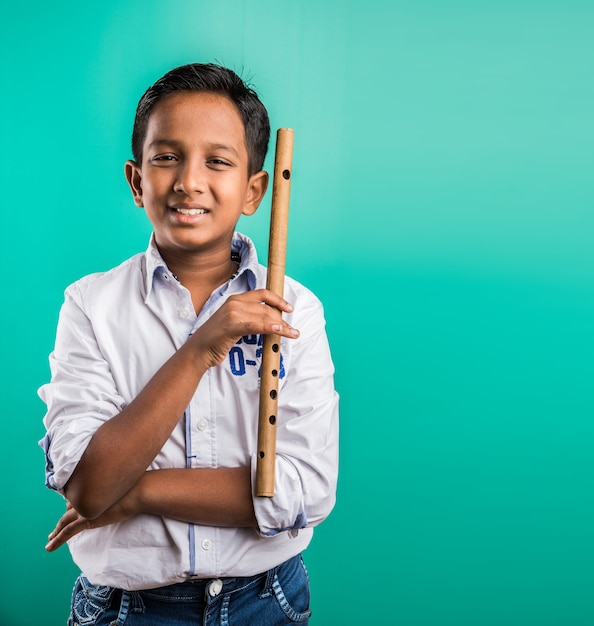 10 year old Indian cute boy playing flute or musical instrument, isolated over green background