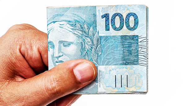 100 reais bills from Brazil held by male hand on isolated white background Banknotes of one hundred reais from brazil payday