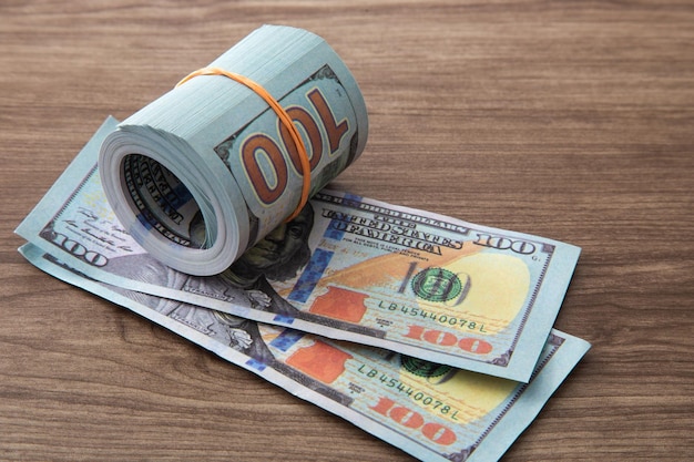 100 US Dollar bills stack on wooden table