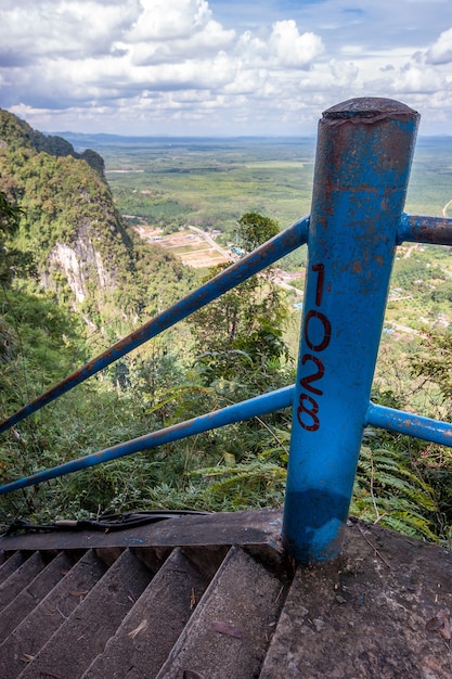 1028 steps on the high staircase at the tiger cave temple in\
krabi province. concrete steps and iron handrails. distance view of\
the rock and fields.