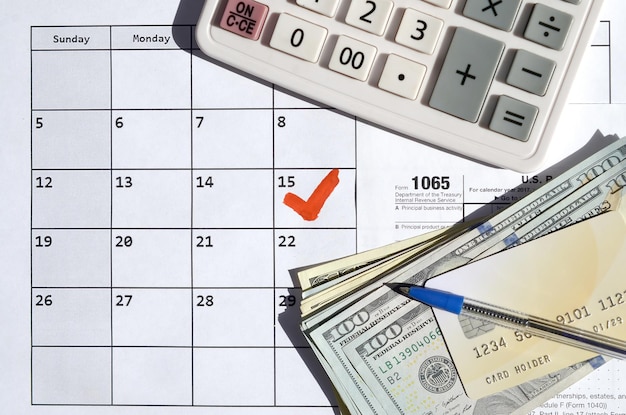 1065 Terugkeer van vennootschapsinkomsten in blank met dollarbiljetten rekenmachine en pen op kalenderpagina met het teken 15 april