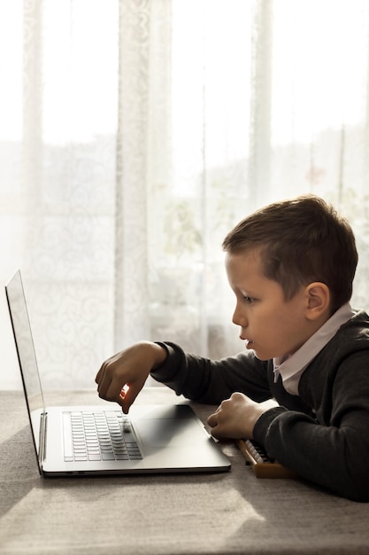 10yearold boy carefully studies using a laptop typing on a keyboard