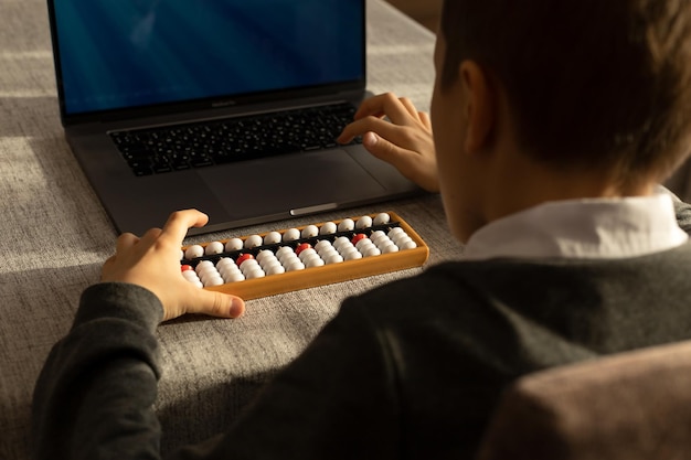 A 10yearold boy learns mental math with a laptop and abacus