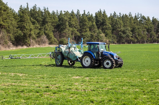 11 of April2018 Vinnitsa Ukraine Tractor spraying insecticide to the green field agricultural natural seasonal spring background