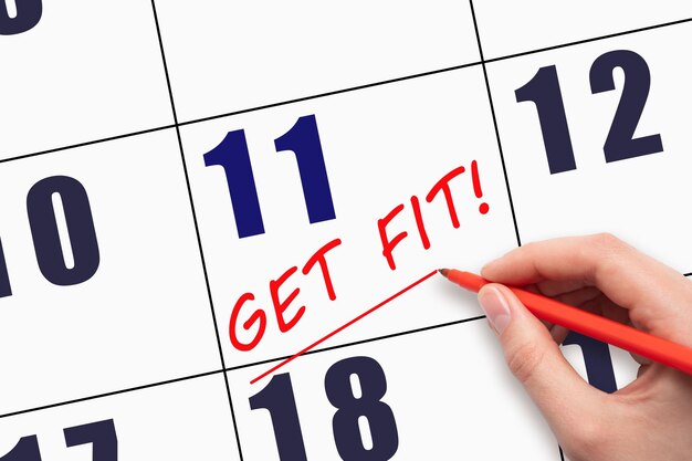 11th day of the month Hand writing text GET FIT and drawing a line on calendar date Save the date