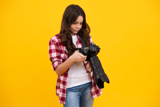 12 13 14 year old teen girl holding digital camera or dslr over yellow background