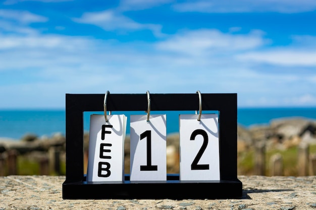 12 februari kalender datum tekst op houten frame met wazige achtergrond van de oceaan kalender datum concept