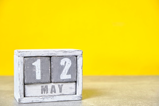 12 mei kalender gemaakt van houten kubussen gele achtergrond met een lege ruimte voor uw tekst International Day verpleegkundige