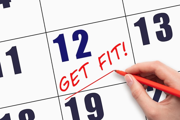 12th day of the month Hand writing text GET FIT and drawing a line on calendar date Save the date