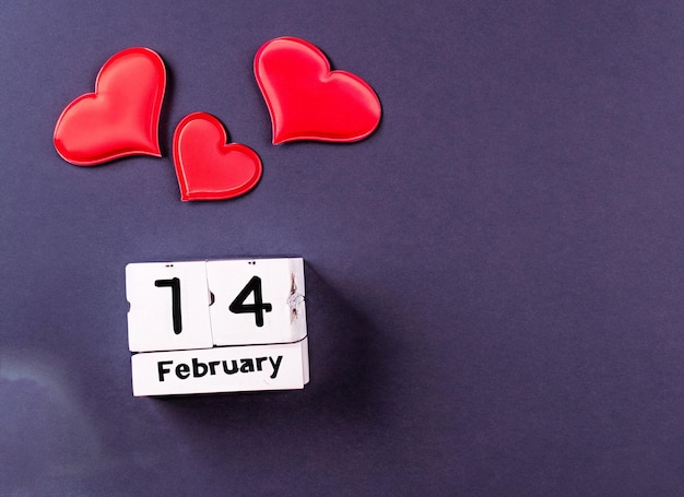 14 februari kalender met papieren hart op een donkere houten achtergrond met kopieerruimte
