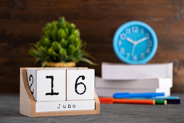 16 juni: Houten kubuskalender met wazige objecten op de achtergrond.