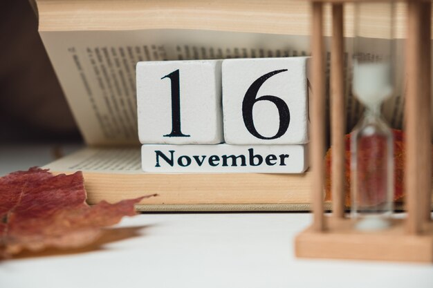 16 november in calendar made from white cubes on book with autumn leaf