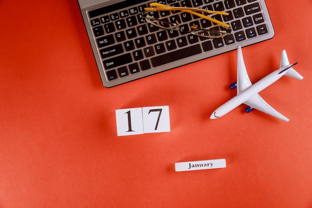 17 januari kalender met accessoires op zakelijke werkruimte bureau op computertoetsenbord, vliegtuig, glazen rode achtergrond