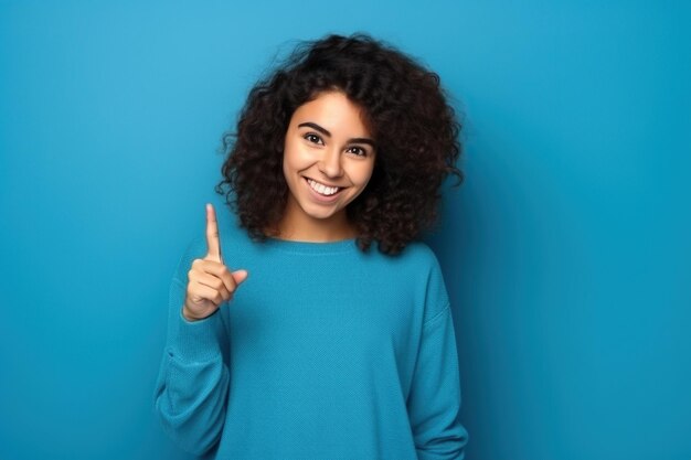 A 17 years old girl on a blue background gesticulates with her index finger, copy space