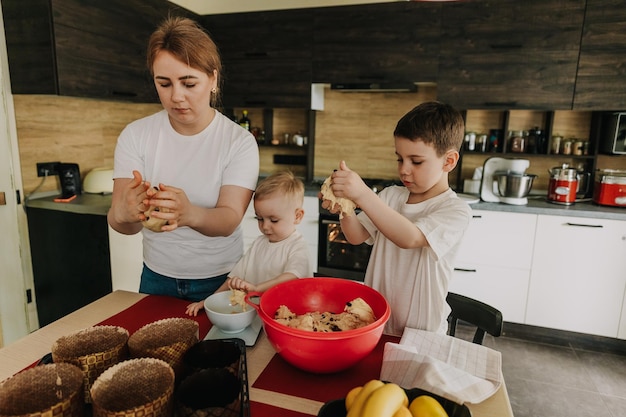 18112018 Vinnitsa Ukraine mom with children kneads the dough for delicious pastries that they prepare in the kitchen at home