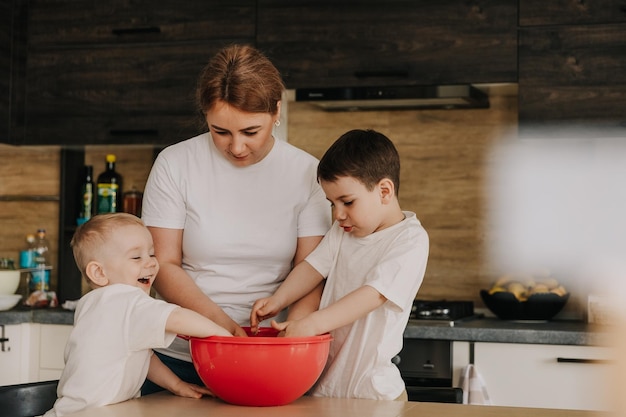 18112018ヴィーンヌィツャウクライナのお母さんと子供たちは、自宅のキッチンで調理するおいしいペストリーの生地をこねます