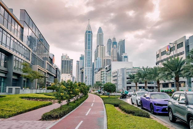 19 januari 2023 Dubai UAE City straat met fietspad en geparkeerde luxe auto's in Internet City district met Marina wolkenkrabbers op de achtergrond