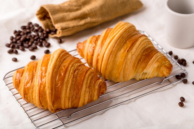 2 croissants worden op een rooster geplaatst en koffiebonen worden gegoten uit zakken verspreid over de vloer, ontbijt, snacks of bakkerij.
