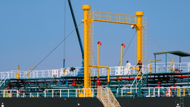 2 engineers walking on steel walkway over oil pipelines system while working in oil tanker ship