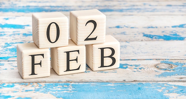 2 februari. Houten kubussen met datum van 2 februari op oude blauwe houten achtergrond.